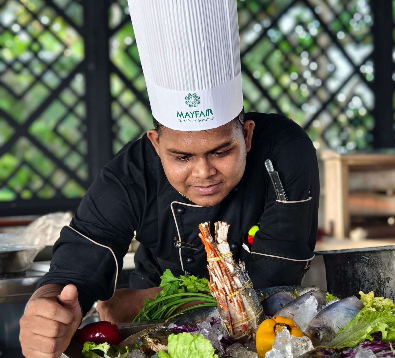 A chef in a Mayfair Hotels uniform preparing fresh seafood with vibrant vegetables